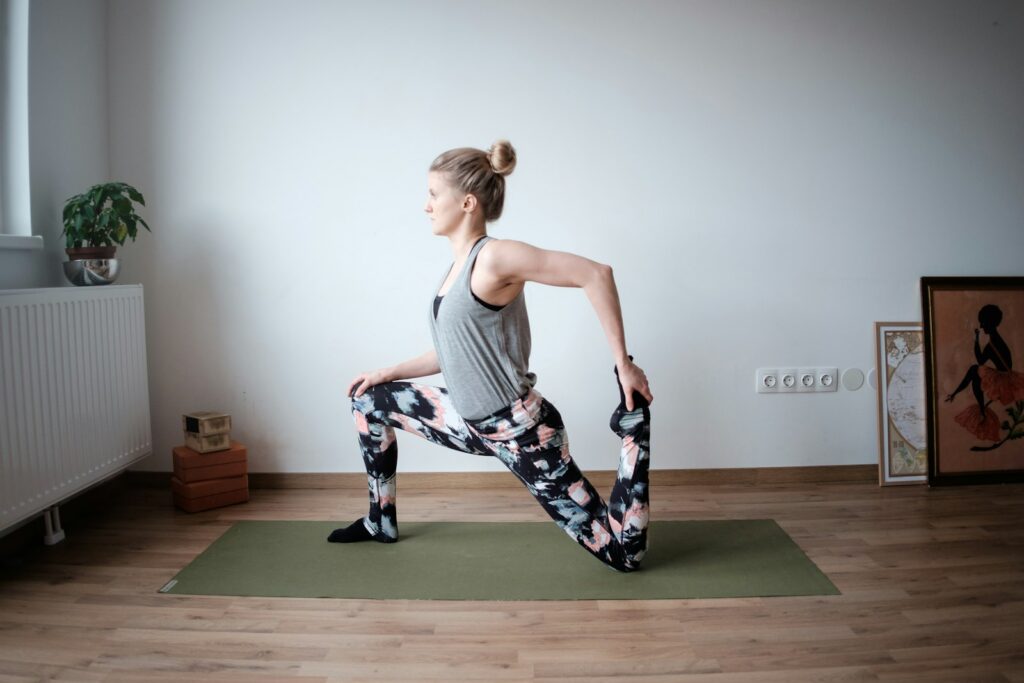 Femme adulte en position de fente avant pour étirer le quadriceps, sur tapis vert
