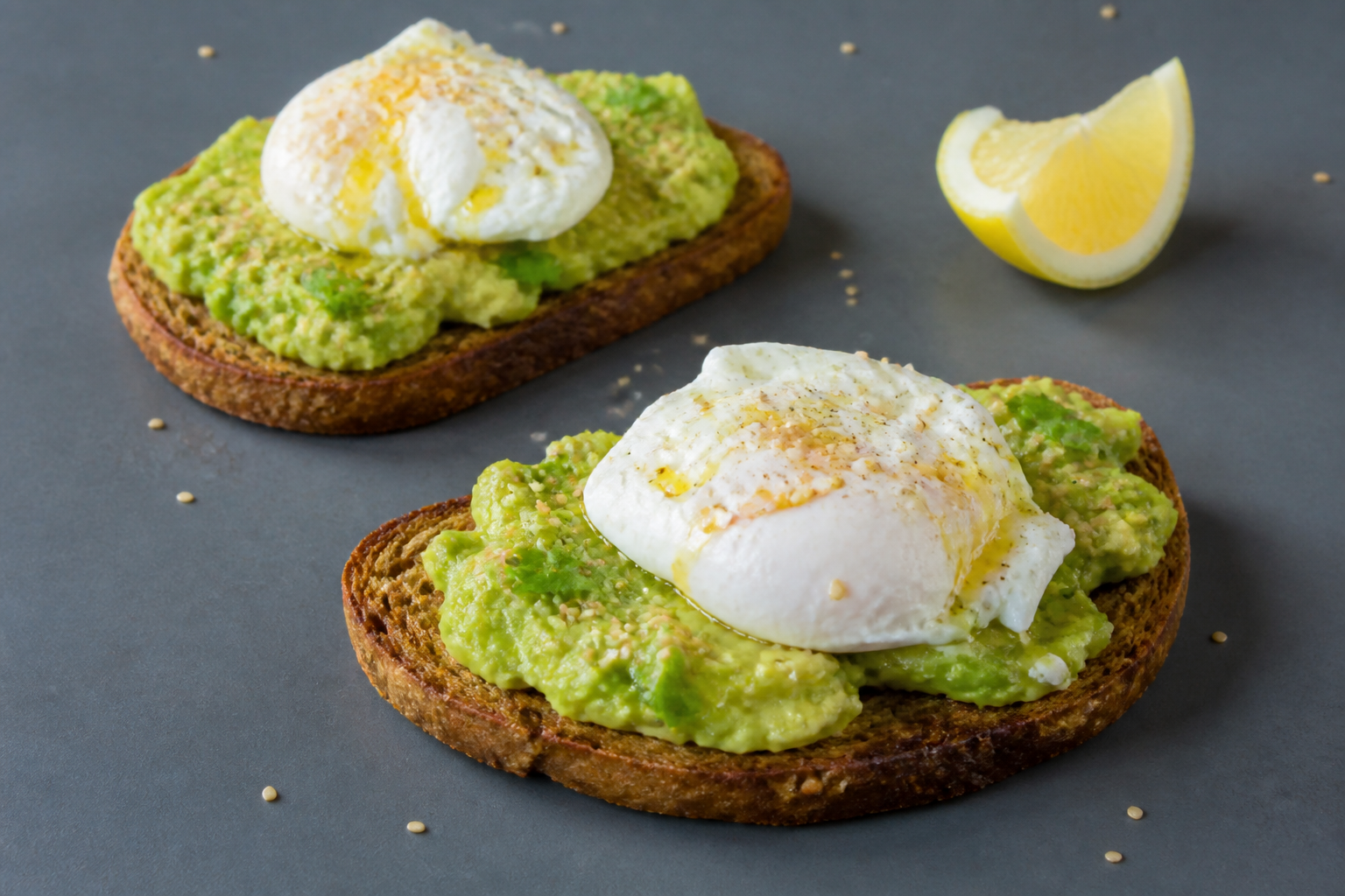 Deux tartines de pain complet à l'avocat écrasé et œuf poché avec graines de sésame — idée de petit-déjeuner protéiné